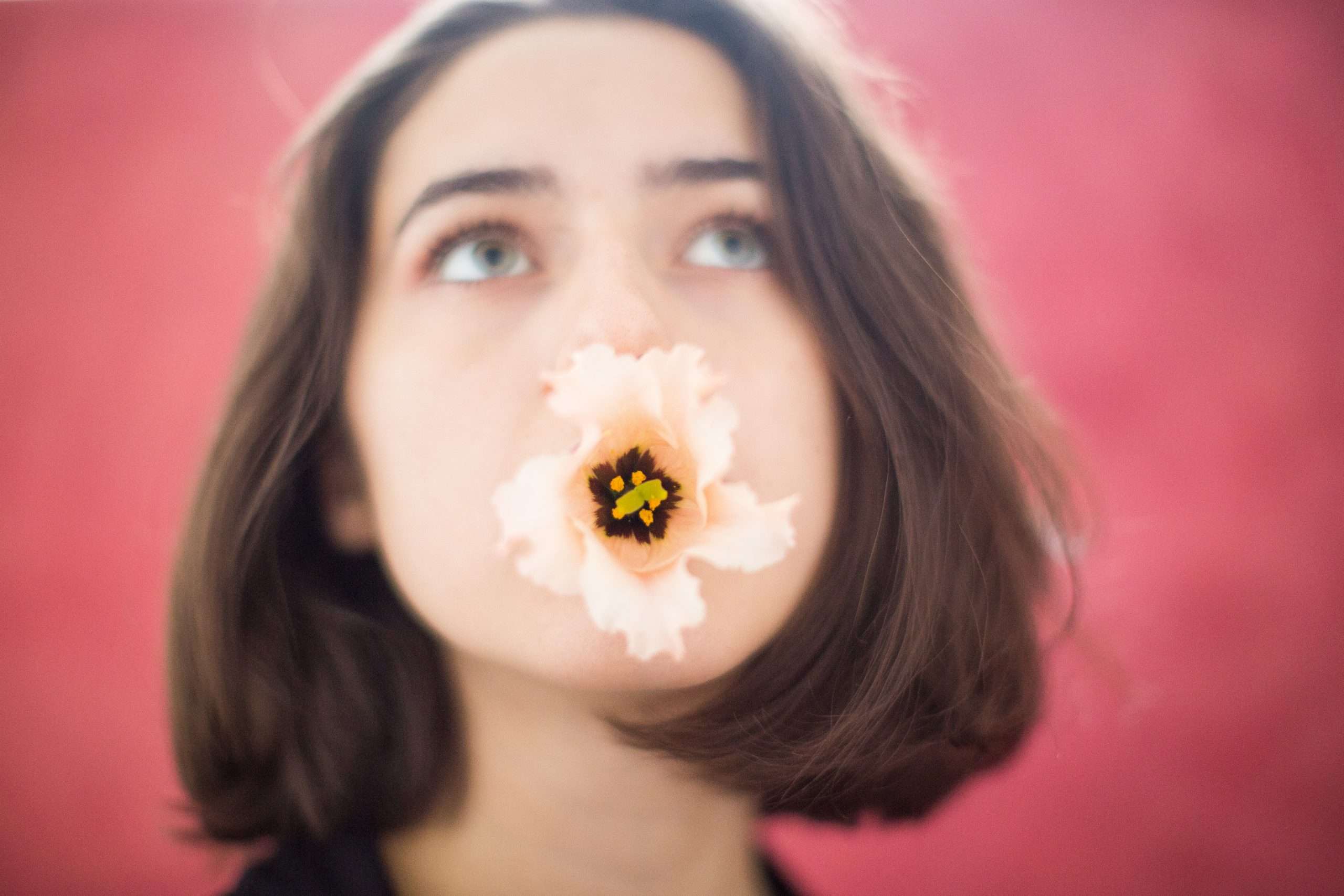 portrait of a woman looking skyward with a flower in her mouth