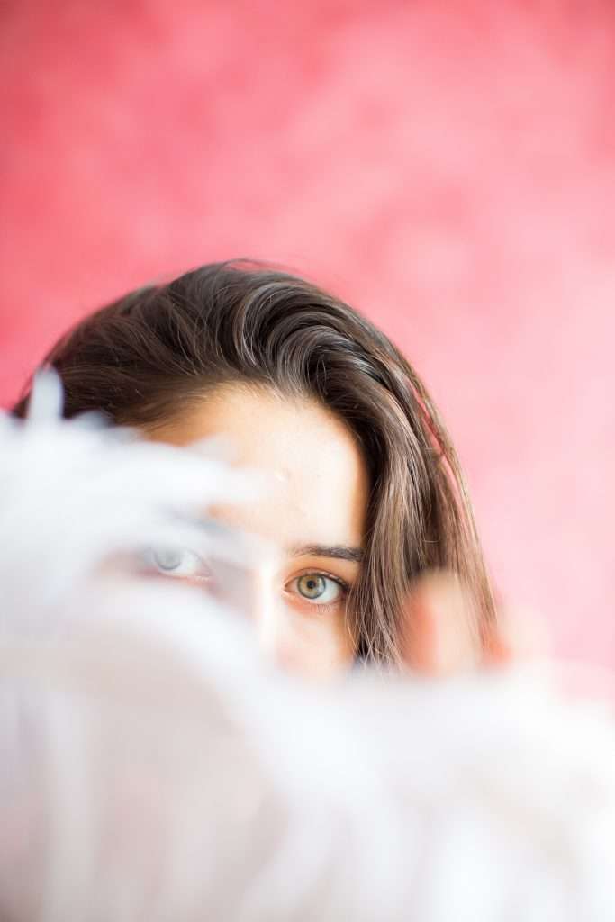 Portrait Photography for Women London - woman peering confidently from behind feather