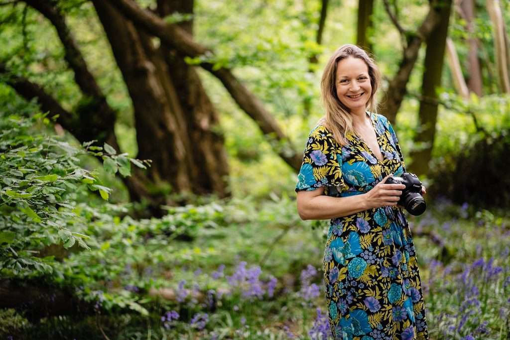 Frances Carlisle Spirited -London Brand Photographer, with camera in bluebell forest