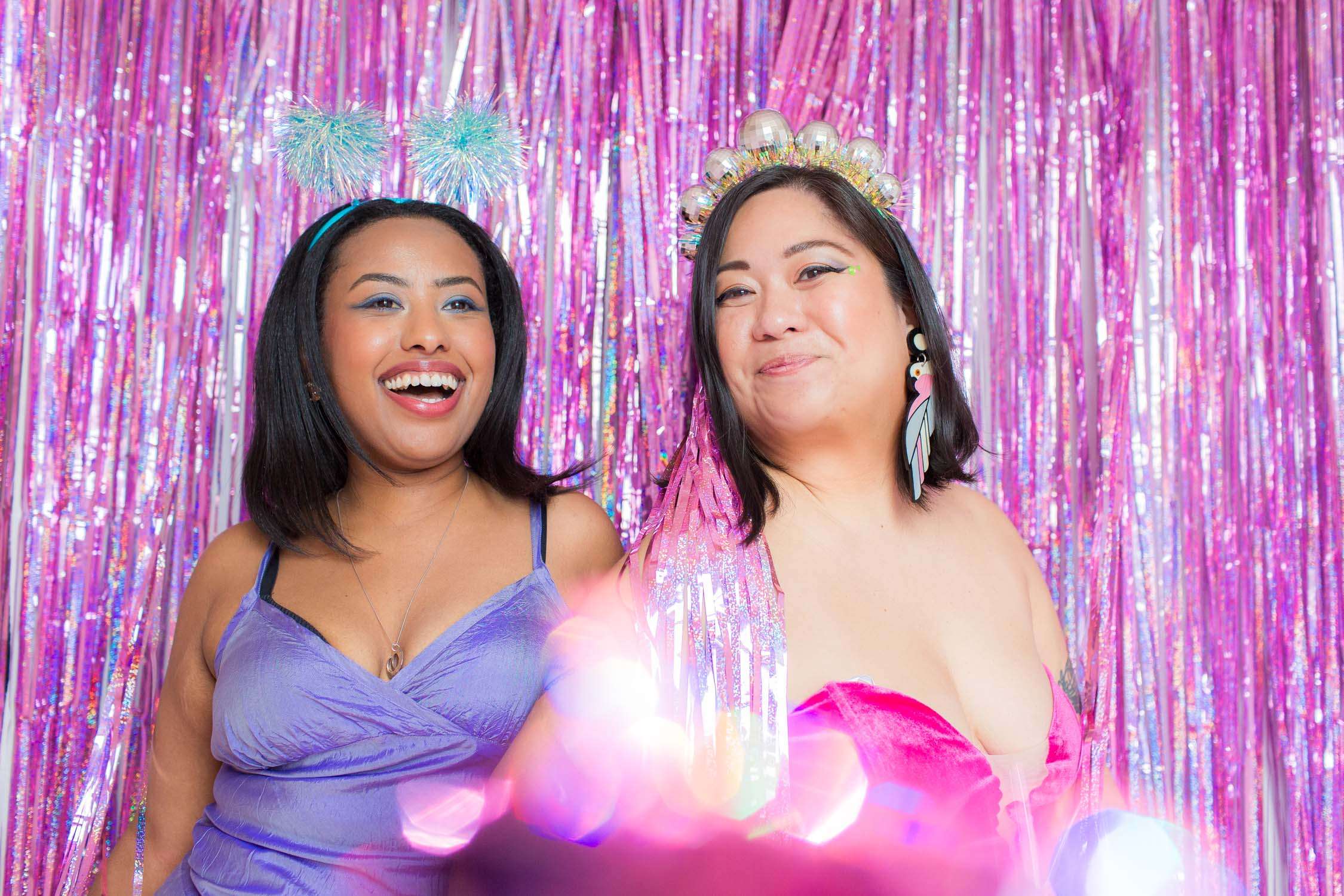 Bitches in Stitches women comedians having fun with a glitter background wearing disco ball and glitter pom pom headdresses