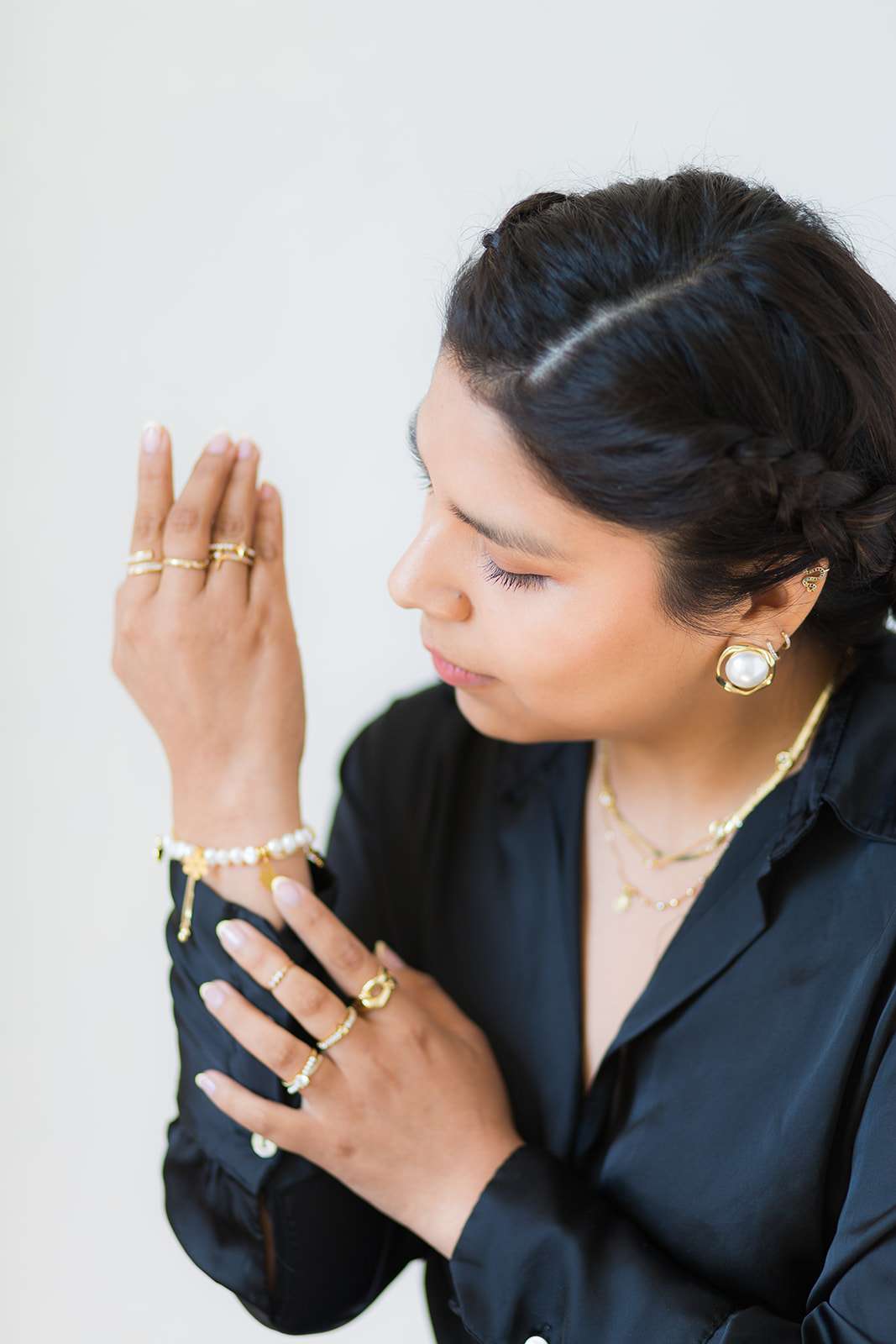 Woman dressed in black with hand held up pulling sleeve down to show jewellery in images for brand product photos