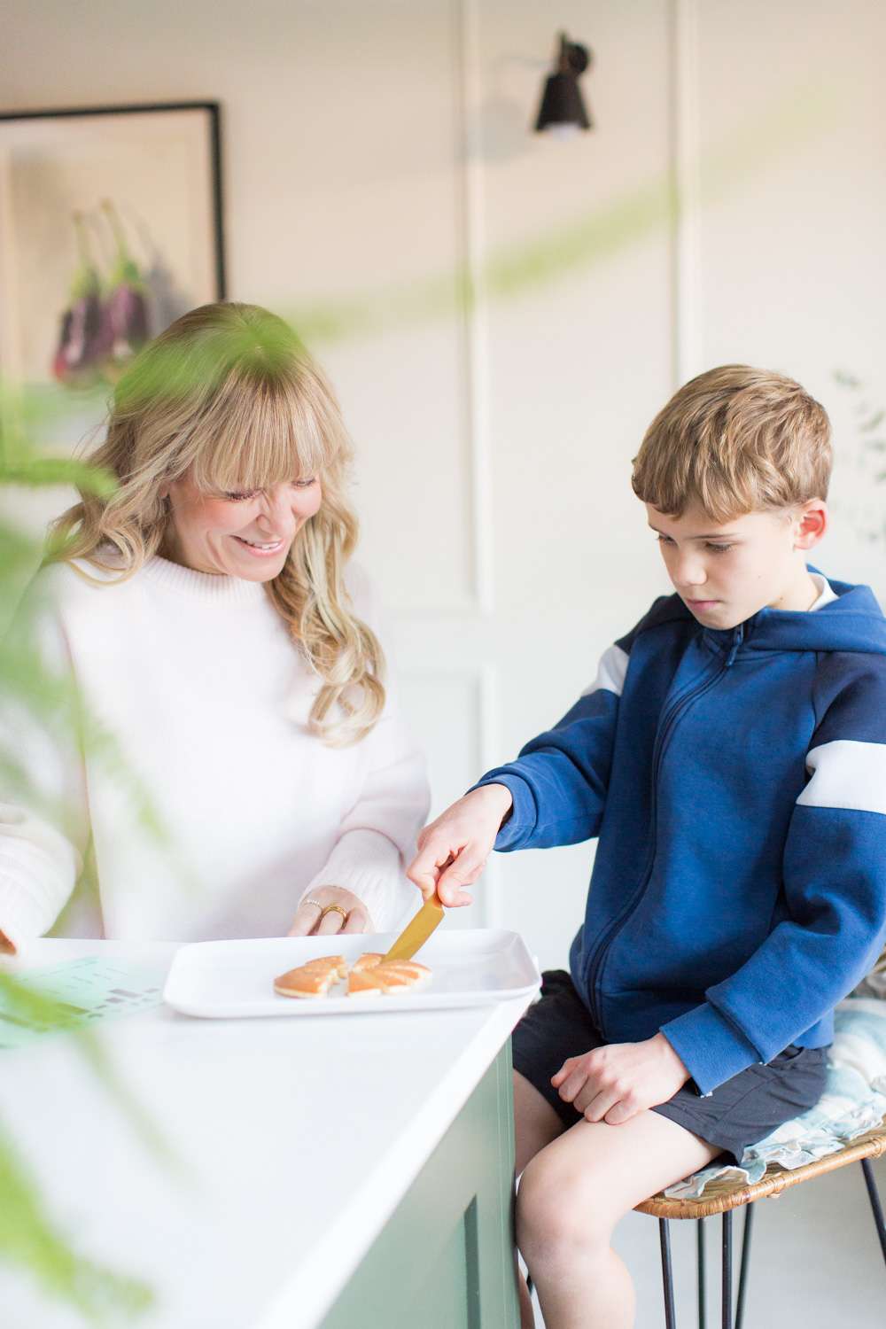 Tutor in kitchen teaching fractions to a child who is dividing a pancake with a knife